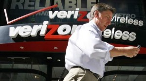 A man looks at his phone as he walks past a Verizon wireless store in New York