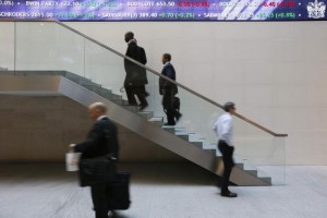 People walk past an electronic information board at the London Stock Exchange in the City of London