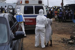 Health workers bring woman suspected of having contracted Ebola virus to an ambulance in front of a crowd in Monrovia
