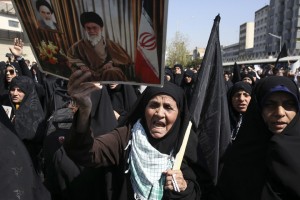 An Iranian worshipper holds a poster of Iranian Supreme Leader Ayatollah Ali Khamenei, and late revolutionary founder Ayatollah Khomeini, at top left of the poster as she chant slogans while attending an anti-Saudi protest rally on Thursday, after their Friday prayer service in Tehran, Iran, Friday, Sept. 25, 2015. Thousands of Iranian worshippers have marched in Tehran after Friday prayers to denounce the "incompetency" of Saudi Arabia in handling the annual hajj pilgrimage. The protest came a day after at least 719 pilgrims died during a crush on the outskirts of the holy city of Mecca. (AP Photo/Vahid Salemi)