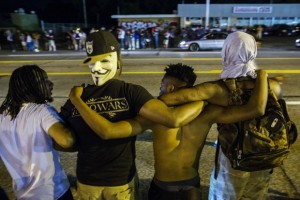 Protesters lock arms as they chant towards police officers during another night of demonstrating in Ferguson, Missouri August 11, 2015. A state of emergency that was declared on Monday for the Ferguson area was still in effect on Tuesday. Protesters have been marching and staging acts of civil disobedience over police shootings of unarmed black men. REUTERS/Lucas Jackson  - RTX1NZEI